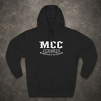 A black pullover hoodie laid flat on a textured gray background, featuring a white graphic print on the chest that reads 'MCC' with 'EST. 2026' and 'MONORCYCLE & CAR CULTURE' below.