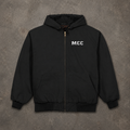 A black zip-up hooded jacket with 'MCC' printed in white on the left chest, laid flat on a textured gray concrete background.